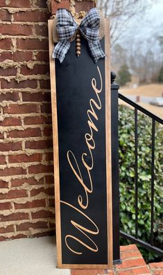 a welcome sign hanging from the side of a brick building with a bow on it