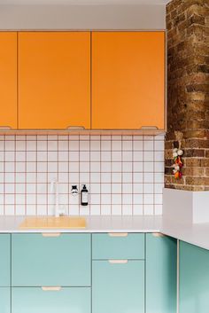 an orange and blue kitchen with white counter tops