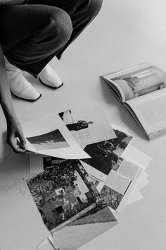 a person sitting on the floor next to some books and papers that have been cut open