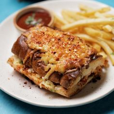 a sandwich and french fries are on a white plate with blue tablecloth, along with condiments