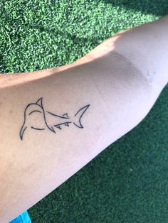 a small tattoo on the arm of a person's left arm with two sharks