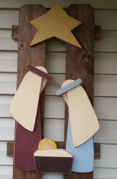 a nativity scene made out of wood on the side of a house with a star above it