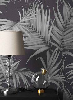 a lamp on a night stand next to a wallpapered with palm trees and leaves