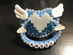 a pacifier with angel wings and beads on it's side sitting on a table