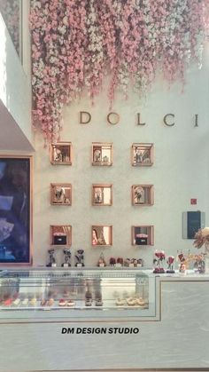 a display case in a store filled with lots of pink flowers and pictures on the wall