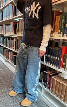 a man standing in front of a bookshelf with his hand on his head