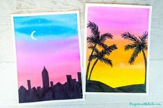 two cards with palm trees and the moon in the sky, on top of a wooden table