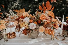 an arrangement of flowers and candles on a table