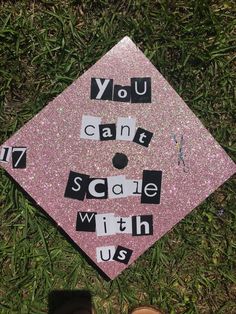 a pink graduation cap that says you can't scare with us on the grass