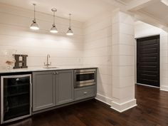 an empty kitchen with white walls and wood flooring is pictured in this image, there are lights on the ceiling