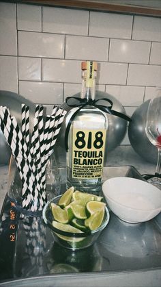 a bottle of tequila and some limes on a counter