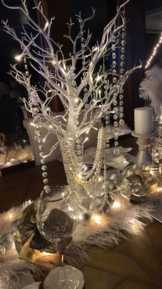 a table topped with lots of white christmas decorations and lit up trees on top of it