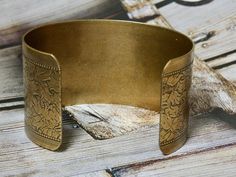 This bracelet is a brass metal cuff with a repurposed vintage repurposed brooch glued on top. A great gift for the vintage lover in your life. IT E M ∙ S P E C I F I C A T I O N S: - CUFF: Metal cuff is brass with a engraved floral detail and measures 6" X 1 1/2" - EMBELLISHMENT: Blue and clear rhinestone brooch is prong set and measures 1 1/2" x 1 1/8" C A R E ∙ T I P S: We don’t want your special moment to fade. To maintain the quality of your jewelry, please: - Do not wear it to the pool, spa Vintage Stamped Cuff Bracelet For Wedding, Vintage Bronze Bracelets For Gifts, Vintage Brass Bracelet Gift, Antique Gold Metal Cuff Bracelet As Gift, Vintage Bronze Bracelets For Gift, Antique Gold Metal Cuff Bracelet For Gift, Adjustable Vintage Gold Cuff Bracelet, Victorian Gold Cuff Bracelet Gift, Vintage Brass Bracelets Nickel Free