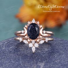 an engagement ring with a black diamond surrounded by white diamonds on top of a rock