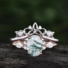 a close up view of a ring with an aqua green stone and white diamonds on it