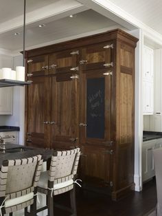 a kitchen with a chalkboard on the back of it's cabinet and chairs