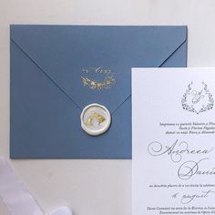 a blue envelope with a ring on it next to a white and gold wedding card