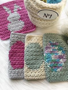 four crocheted pot holders are sitting on a white surface next to some flowers