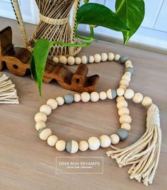 a white and grey beaded necklace next to a potted plant on the floor