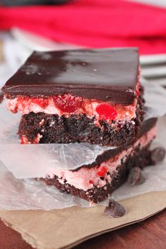 two pieces of cake sitting on top of paper next to chocolate chips and strawberries