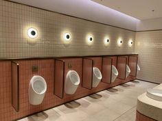 a row of urinals mounted to the side of a wall in a bathroom