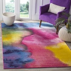 a brightly colored rug in a living room with purple chair and potted plant on the floor