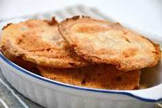 two pieces of fried food in a white dish on a tablecloth with a fork