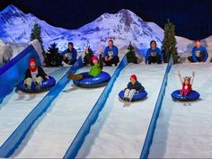 several people are riding down an inflatable snow hill with skis and sleds