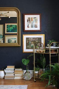 a living room filled with lots of plants and pictures on the wall next to a mirror