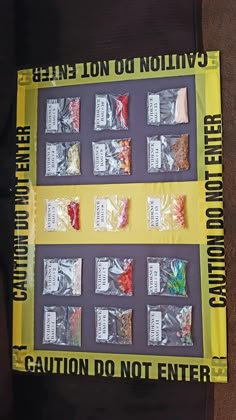 a yellow caution sign sitting on top of a wooden table next to bags of candy