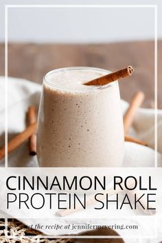 cinnamon roll protein shake in a glass with cinnamon sticks