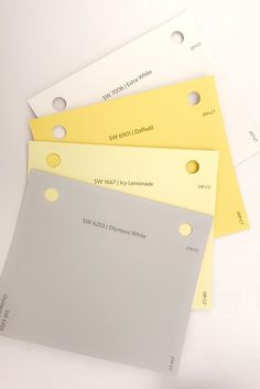 four different colors of paper with holes in the middle and two are yellow, one is white