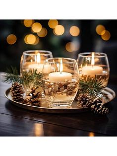 three lit candles are sitting on a tray with pine cones