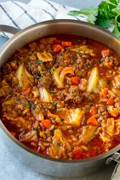 a large pot filled with meat and vegetables on top of a table next to a spoon