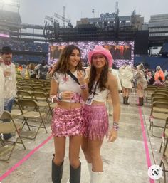 two young women standing next to each other in front of a stadium filled with people