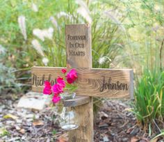 a wooden cross with flowers on it and the words forever in our hearts written on it