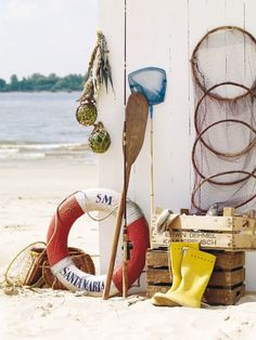 there are many items on the beach by the wall that is covered in fishing nets and buoys