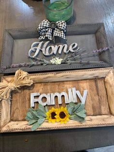 a wooden sign that says home and family with sunflowers in the center on a table