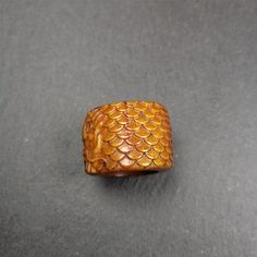 a wooden ring with fish scales on the inside and outside, sitting on a gray surface