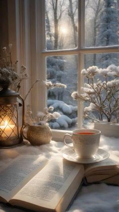 an open book and cup sit on a window sill next to a lit candle