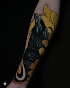 a person with a black and yellow tattoo on their arm is holding a small bird