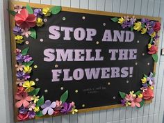 a sign that says stop and smell the flowers on it in front of a tiled wall