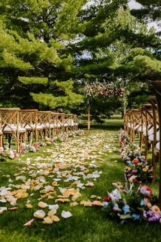 an outdoor ceremony with wooden chairs and flowers on the grass