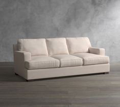 a white couch sitting on top of a wooden floor next to a gray wall in a living room