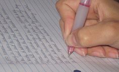 a person is writing on lined paper with a pen