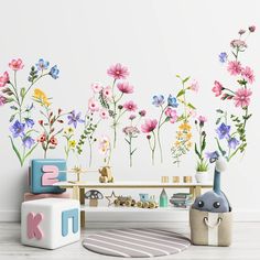 a room with flowers painted on the wall and toys in front of it, including an elephant