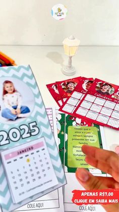 a person is holding up a calendar on a table with other items in the background