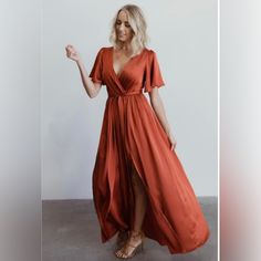 a woman in an orange dress posing for the camera with her hand on her hip