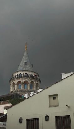 a white building with a gold dome on top and dark clouds in the sky above