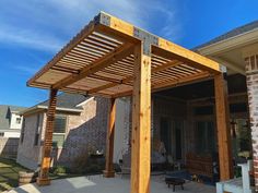 a wooden pergolan sitting on top of a patio next to a brick building